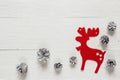 Red decorative deer and snow painted pine cones on rustic white