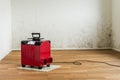 Red dehumidifier in an empty room with a toxic mold and mildew problem