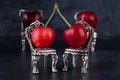 Red delicious ripe cherries on silver chairs and dark background Royalty Free Stock Photo