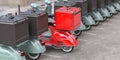 Red delivery scooter with delivery bag in a row of mopeds of grey color. Fast express delivery concept