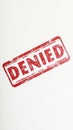 Red denied stamp on white paper showing rejection or refusal
