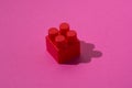 Red detail cube of children`s constructor on a pink background