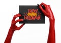 Red devil hand with black nails holding a paper card with the words Happy Halloween Royalty Free Stock Photo