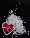 A red diamond or a large ruby in the shape of a heart, a symbol of love or Valentine`s Day. A red diamond is placed on a pile of Royalty Free Stock Photo