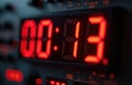 Red digital numbers show time 00 13 on electronic device. Close-up view of modern LED display, countdown timer. Dark background Royalty Free Stock Photo