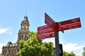 Red Directions arrow sign pointing to famous places with the clock tower at Bendigo\'s town hall on main street in CBD. Royalty Free Stock Photo