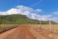 Red dirt road leading to a green hill in the Brazilian cerrado