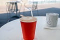 Red disposable cup of coffee standing on a white table Royalty Free Stock Photo