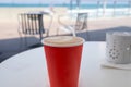 Red disposable cup of coffee standing on a white table Royalty Free Stock Photo