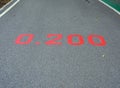 A red distance sign numbers 0.200 KM marken on surface the street in the parks