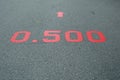 A red distance sign numbers 0.500 KM marken on surface the street in the parks