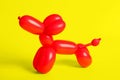 Red dog figure made of modelling balloon on yellow background