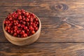 red dog-rose rosehip fruits in a wooden bowl on wooden table