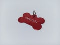 A red dog tag in the shape of a bone with the name and phone number on the back Royalty Free Stock Photo