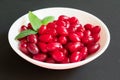 Red dogwood berries in a plate on a black background. Close-up.