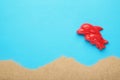 Red Dolphin toy with sand on blue background. Summer composition Royalty Free Stock Photo