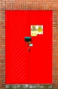 Red door double lock on brick wall.