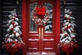 The red door of the house is decorated with a snow-covered Christmas wreath, snow-covered Christmas trees near the door