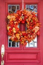 Red door with leaded glass windows and bright autumn wreath - closeup Royalty Free Stock Photo