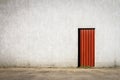 Red door in the middle of a gray concrete wall Royalty Free Stock Photo