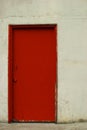 Red door in an off-white stucco wall Royalty Free Stock Photo