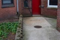 Red door rear entry to old brick apartment building with concrete walkway Royalty Free Stock Photo