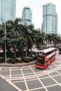 Red double-decker bus passing around palm trees Royalty Free Stock Photo