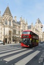 Red double decker bus passing Royal Courts of Justice building