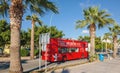 Red double decker the wedding bus with guests on inside driving between palms in Royalty Free Stock Photo