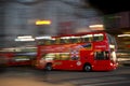 A red doubledeck London bus at night seen with motion blur against blurred lights