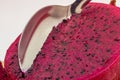 Red dragon fruit, aka Pitaia or Pitaya. Detail of a spoon cutting the pulp of a red pitaya fruit in a macro photo. Royalty Free Stock Photo