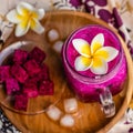 Red Dragon fruit juice in a glass, decorated with Plumeria flower, cut dragon fruit and ice cubes. Served on a round wooden tray o Royalty Free Stock Photo