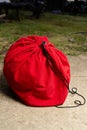 Red drawstring bag resting on outdoor concrete surface with loose black cord Royalty Free Stock Photo