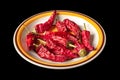 Red dried chili peppers in a round plate. Heap of hot dry peppers on a black background Royalty Free Stock Photo