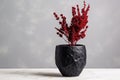 a red dried flower in a black ceramic pot on a marble table Royalty Free Stock Photo