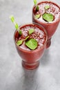 Red drink with green spinach leaves and paper straw in tall glass on bright background. Superfoods, healthy lifestyle concept. Ve