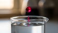 The background is blurred emphasizing the drop and the glass container Royalty Free Stock Photo