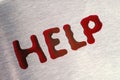 Red drops in the form of a word help. The surface is metallic. Royalty Free Stock Photo