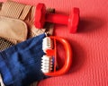 Red dumbbell, brace, knee brace and massager placed on a yoga mat.