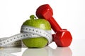 Red Dumbbells, fresh green apple and measuring tape Royalty Free Stock Photo
