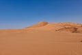 A red circular dune and in the foreground an expanse of undulating sand of the Rub al Khali desert in Oman.