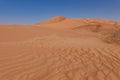 in the foreground the expanse of undulating desert sand in the background a large dune. Oman