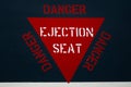 Red ejector seat warning sign on jet fighter aeroplane fuselage. Danger alert message for ejection of pilot.