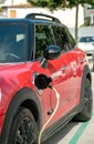 Red electric car at charging station with the power cable supply plugged Royalty Free Stock Photo