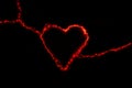 Red electric discharge in the form of a heart on a black background. Greeting card for valentines day. Bright light effect. The Royalty Free Stock Photo