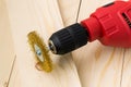 Red electric drill with round metal wire brush for cleaning of metal and wood and remove rust over rough wooden surface.
