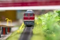Red electric train locomotive model on track layout with trees and bridge Royalty Free Stock Photo