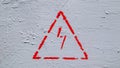 Red electrical hazard sign with lightning in a triangle on a gray painted metal junction box