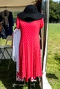 Red elegant fashion ladies red dress with short sleeves with a small white dots design and black felt hat presented on a mannequin