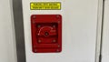 A red emergency door release button with a yellow sticker on it Royalty Free Stock Photo